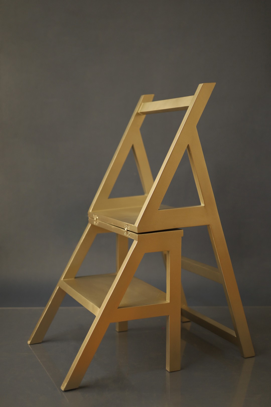 A custom gilded step chair opened into its ladder form, finished in gold